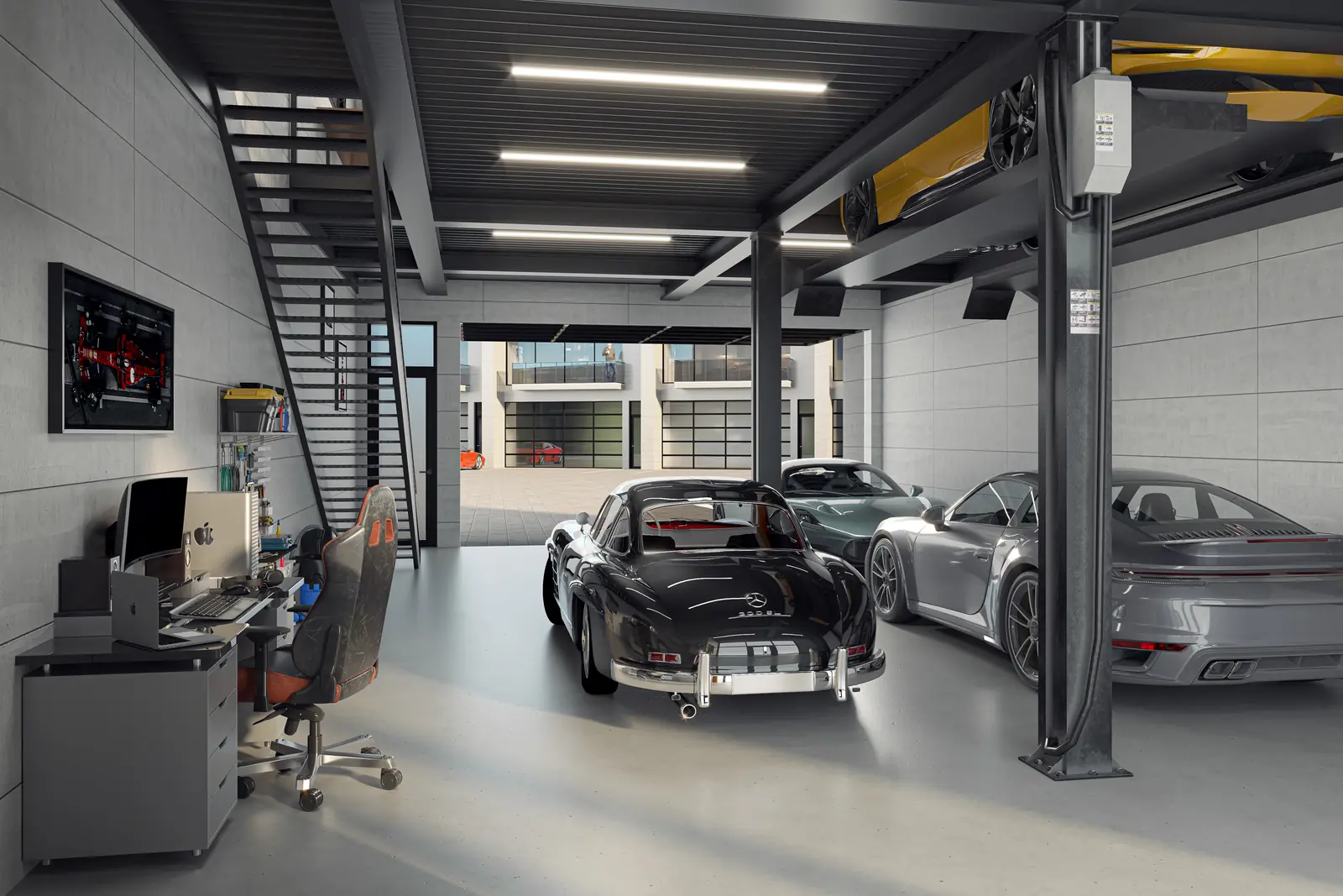Inside a residence at grade: three cars on the showroom floor, a fourth raised on a lift, a work desk and an architectural steel staircase.