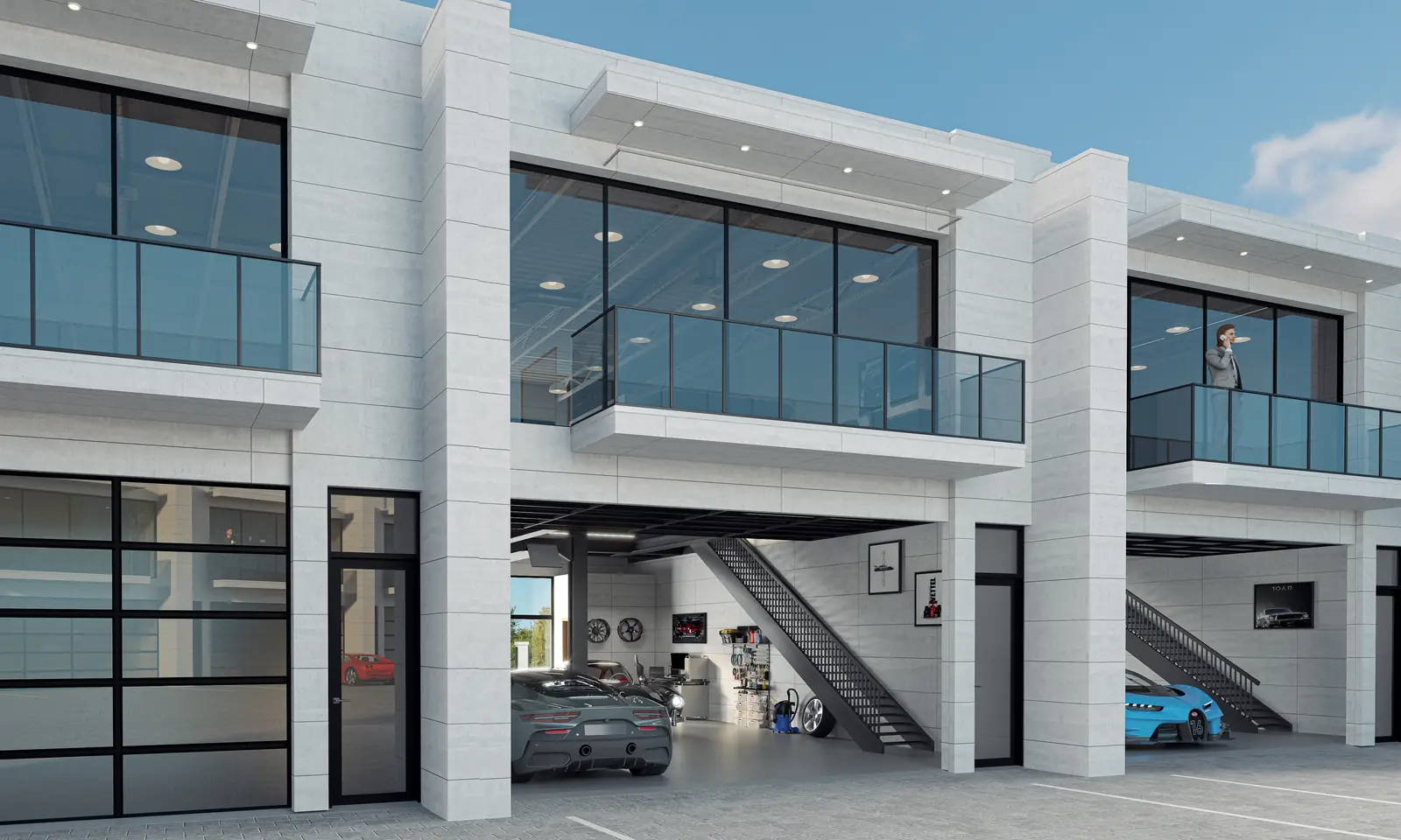 A two-story automotive residence at The Garage with its glass overhead door open, a collection parked inside, an architectural steel staircase, and a glass balcony on the second level.